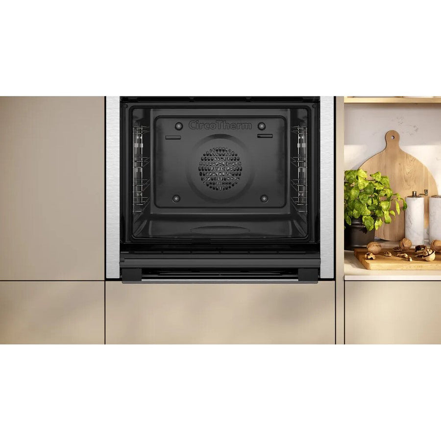 Neff slide & hide oven integrated into a kitchen cabinet with a light-colored backsplash.